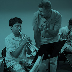 Teacher encouraging young musician playing the trumpet