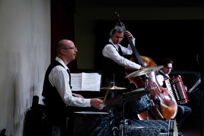 Bass player, drummer, and accordion player performing in a concert