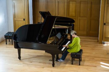 Woman in green plays one of two steinways on stage