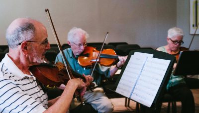 Three elderly musicians playing violin