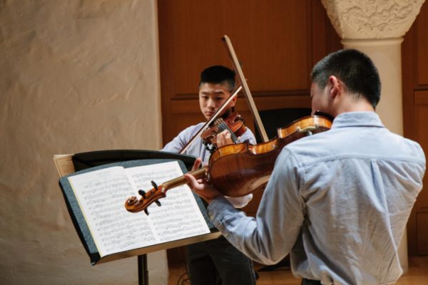 Two young men playing violin