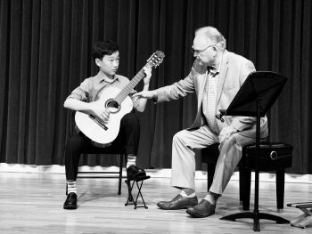 Guitar student with teacher on stage