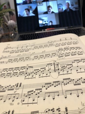 Sheet music in front of a computer with a zoom meeting