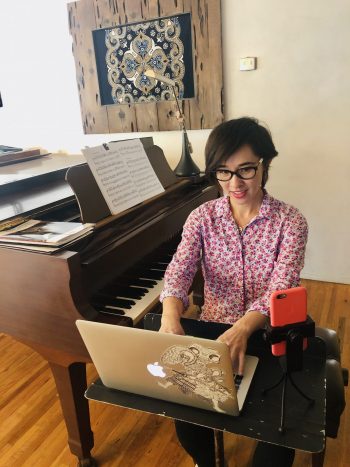 Woman typing next to a piano