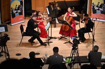 Young violinist, violist, cellist, and violinist play for an audience