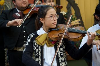Young girl plays violin with a mariachi band
