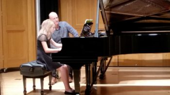 Girl being coached by male teacher at the piano