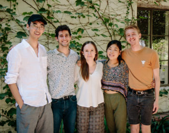 5 young adults posing for a picture in the courtyard