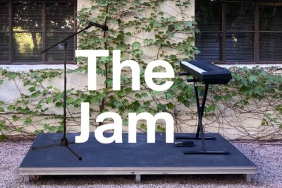 Image of text The Jam on a stage with a piano and microphone