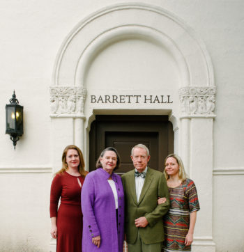 Three women and one man pose in front of Barrett Hall entrance