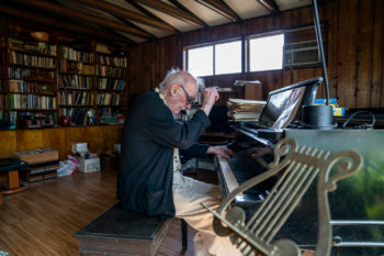 George Crumb playing a piano in his home studio