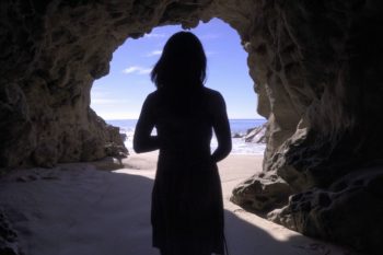 Silouette of woman in cave looking out to the ocean