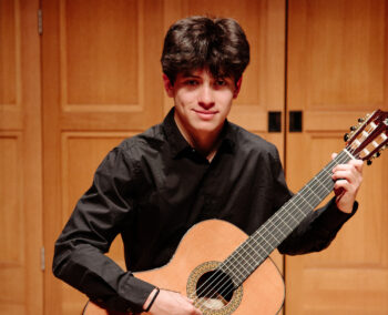 Young man in black playing guitar