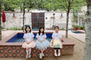 Three girls in tutus sit at the fountain