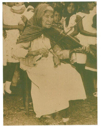 An old photo of an older mexican woman playing violin