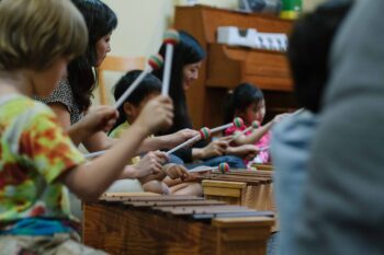 Children hold mallets and play xylophones
