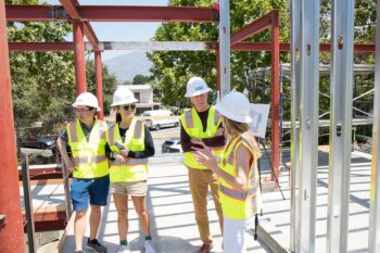 Four people in hard hats tour a construction site