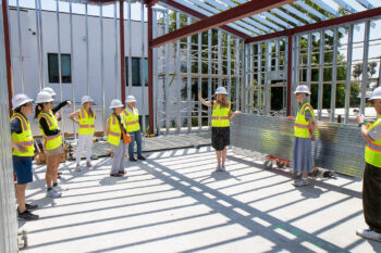 A group in hard hats tours the construction of Common Ground