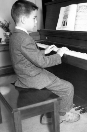 Old photo of a little boy playing piano