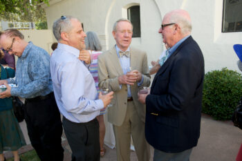 Three men talk candidly in the courtyard