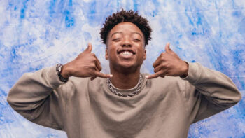 A young man smiles making a shaka symbol with his hands