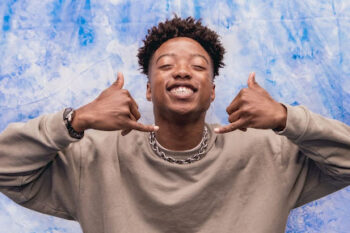 A young man smiles making a shaka symbol with his hands