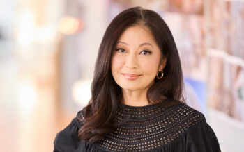 A woman in a black shirt with dark long hair poses