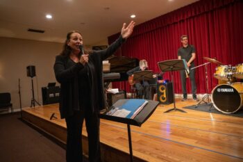 Woman pointing towards the stage with a band behind her