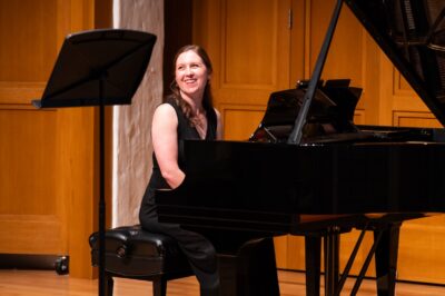 Woman sits at the piano smiling